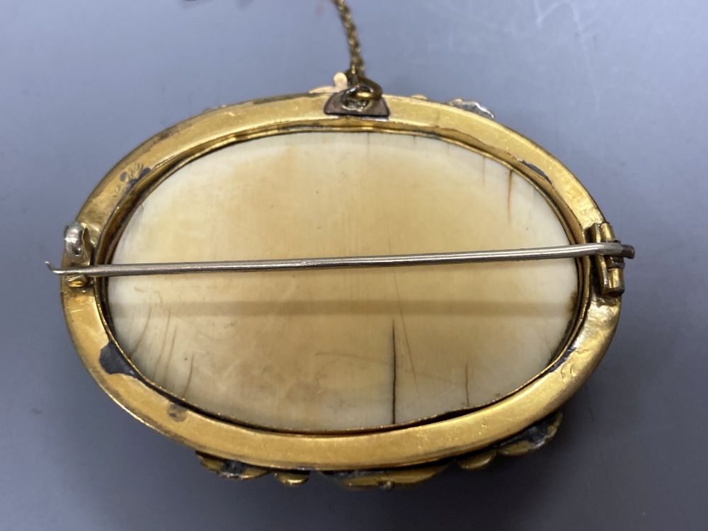 A Chinese gilt metal and ivory oval brooch, 55mm and a silver mounted clay and amberoid cheroot holder.